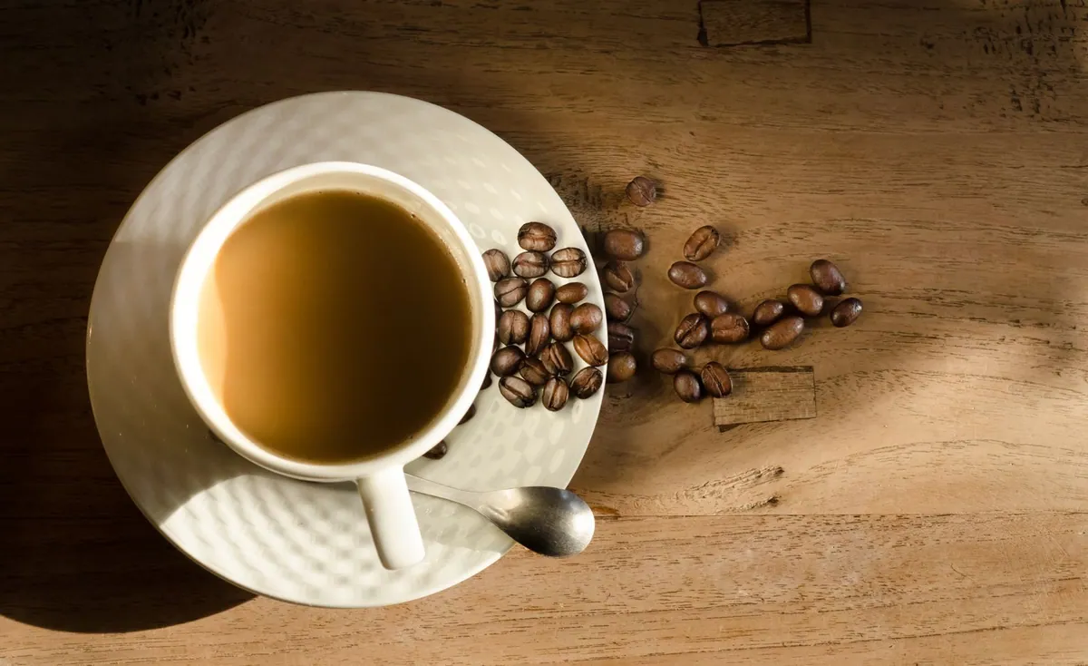 Cup of coffee with roasted coffee beans on a wooden table